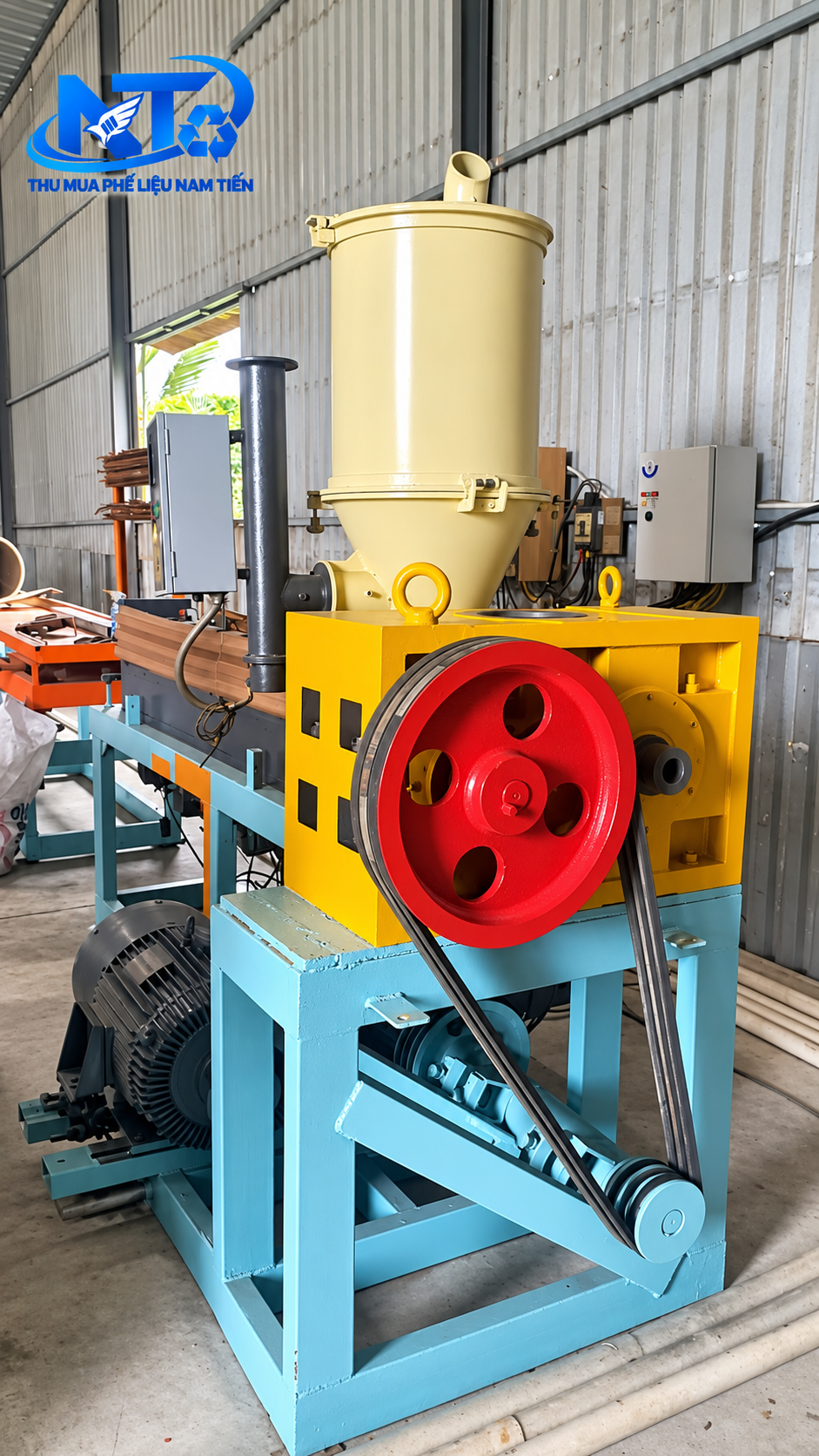 Máy đùn nhựa công nghiệp cũ với phễu nạp liệu, bánh đà và động cơ tại nhà xưởng.